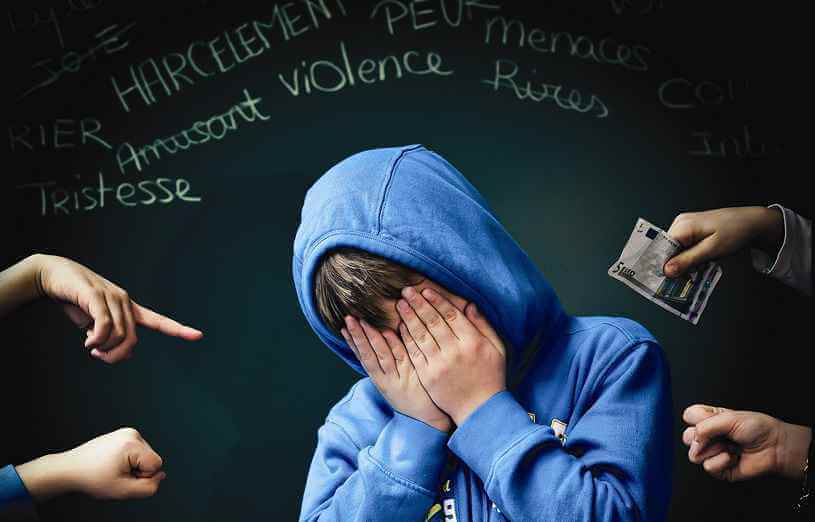 photo d'un jeune garçon qui se tient la tête dans les mains en signe de mal-être face au harcèlement scolaire qu'il subit
