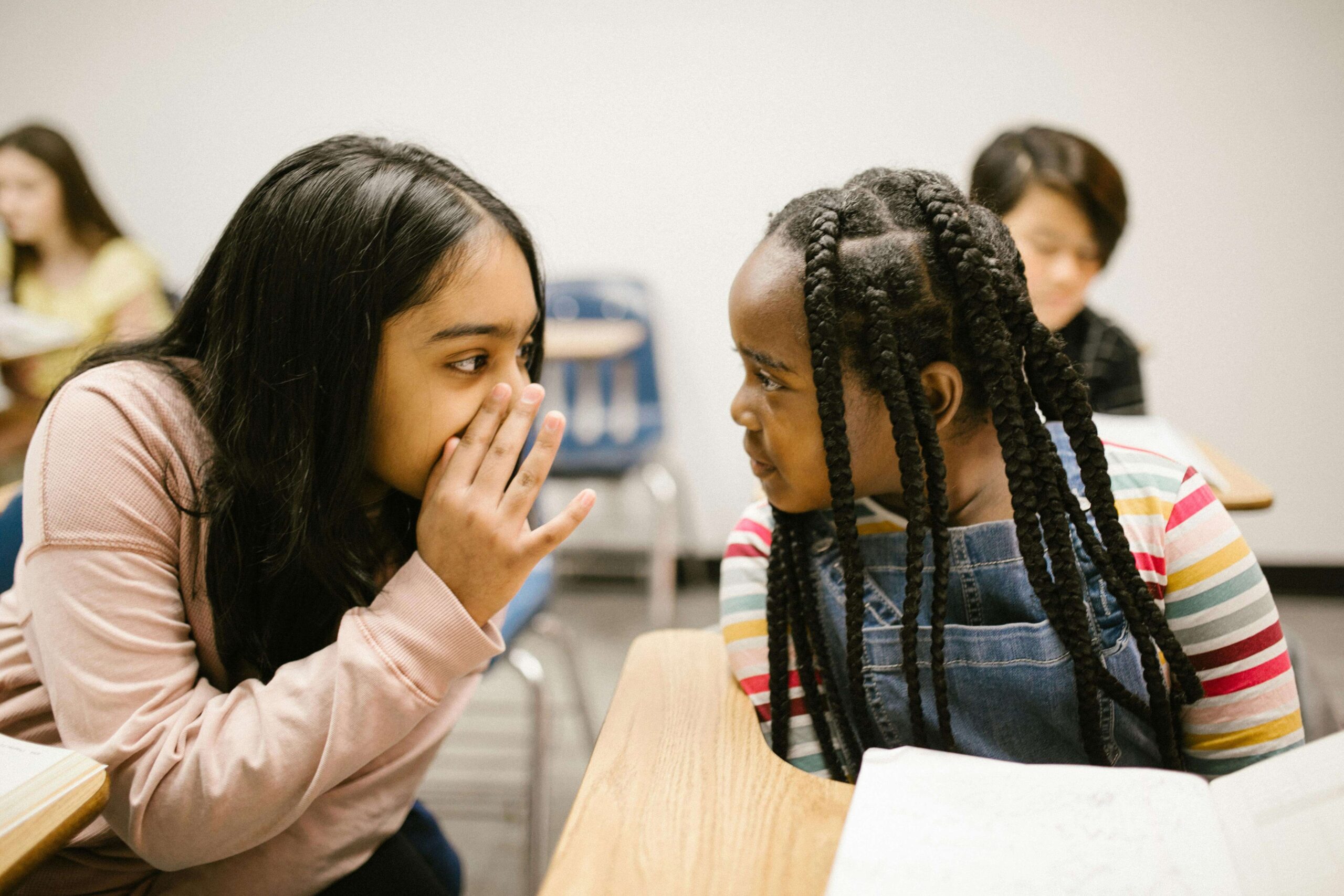 Photo de deux jeunes adolescents qui discutent en classe. Représente les difficultés scolaires qui peuvent amener à consulter un psychologue pour adolescents